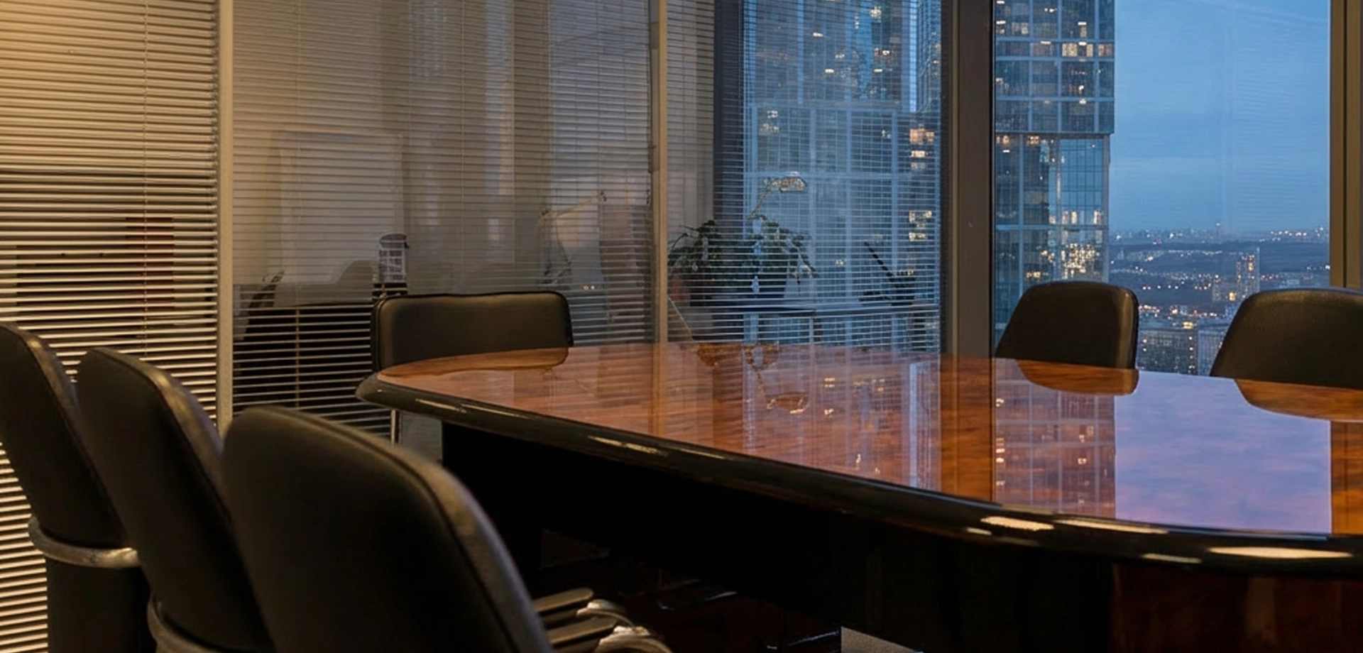 Modern corporate boardroom with conference table and chairs overlooking a city skyline through large windows.