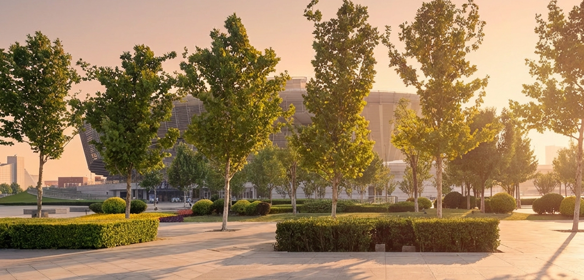 Urban park with trees and landscaped walkways in front of modern buildings at sunrise, representing sustainable development.