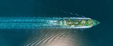 Aerial view of a tanker ship transporting energy resources across the ocean, leaving a wake behind.