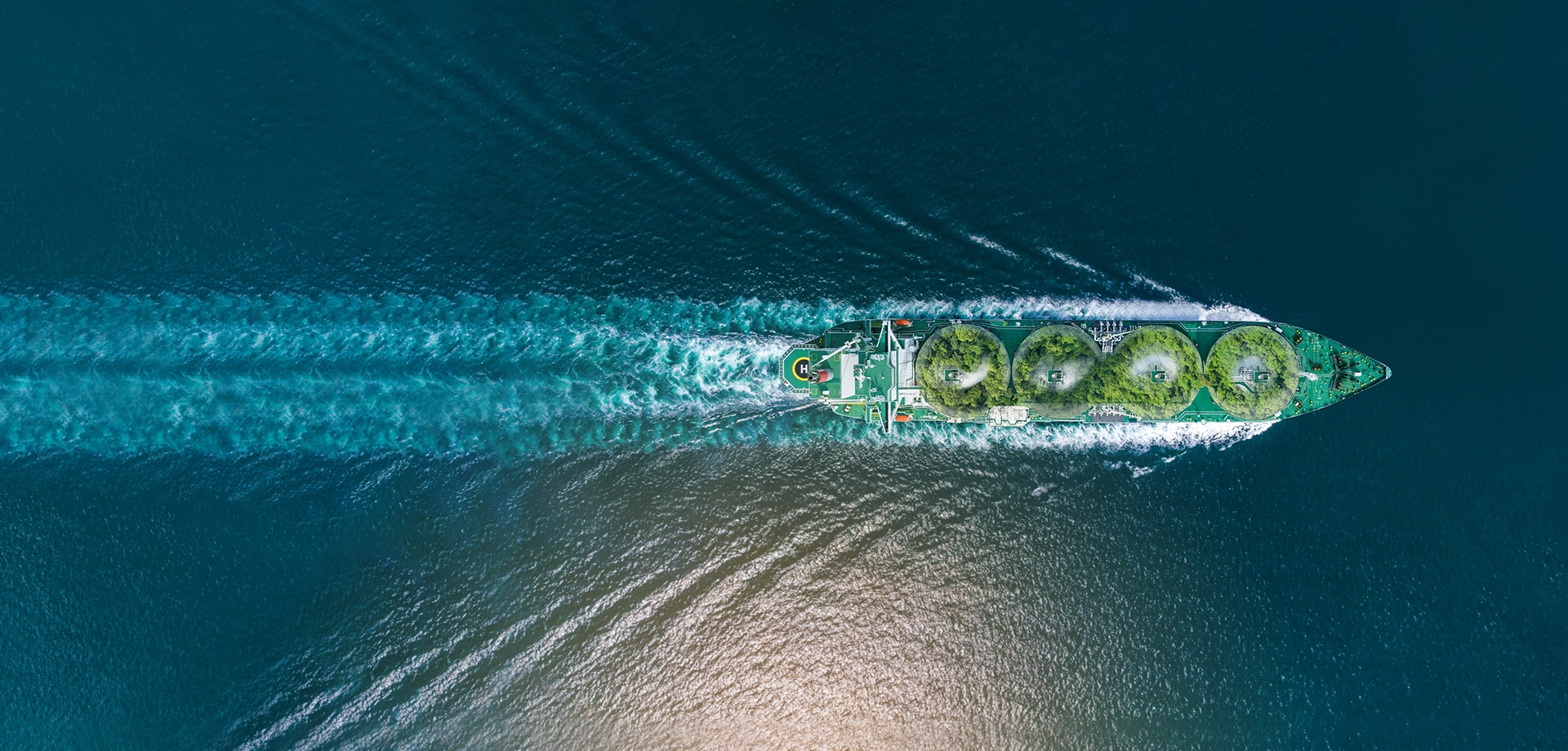 Aerial view of a tanker ship transporting energy resources across the ocean, leaving a wake behind.