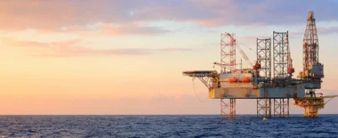 Offshore oil and gas platform in the ocean at sunrise, representing energy production and critical infrastructure.